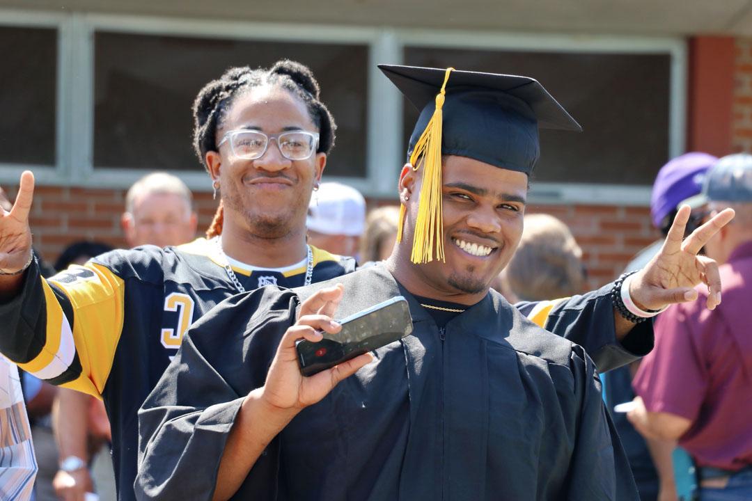 Graduate poses outside of Reed Green Coloseum 